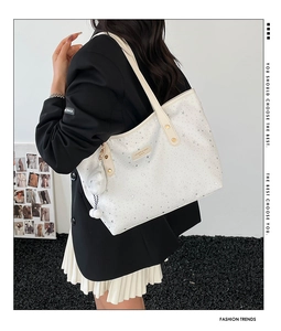Détail du grand sac cabas crème avec motifs d'étoiles argentées et pendentif en peluche