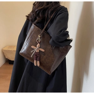 Detail view of large dark brown retro tote bag with a cute rabbit plush charm