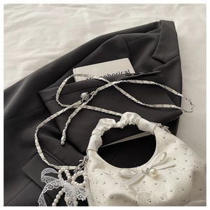 Detail of white cloud bag featuring pearl bow, rhinestone accents and metal chain strap