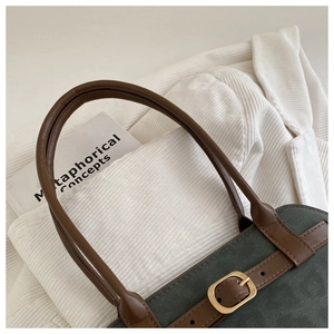 Detail of dark green suede tote bag with brown leather straps and vintage metal buckles