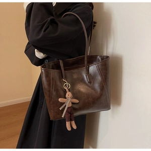 Detail of dark brown faux leather tote bag with vintage oil-wax texture and rabbit charm