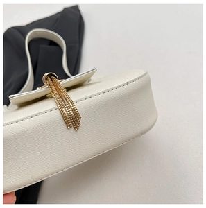 Detail of white Saffiano leather texture on crescent bag with gold tassel charm
