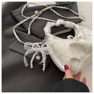Detail of white cloud bag with silver studs and a pearl lace bow pendant