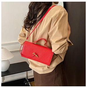 Detail of red woven leather shoulder bag featuring a gold knot clasp and handle