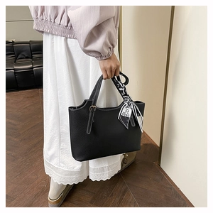Detail of black pebbled leather tote featuring white contrast stitching and a silk scarf