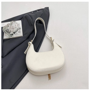 Detail of off-white crescent underarm bag with gold chain tassel and pebble leather texture