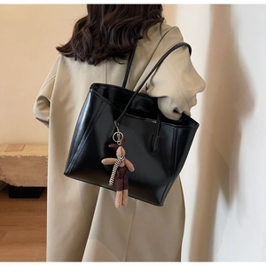 Detail of black faux leather tote bag with a cute brown plush bunny charm accessory
