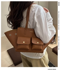 Dettaglio di una borsa tote marrone con trama litchi, occhielli in metallo e design moda