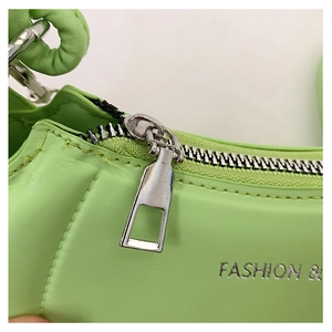 Close-up of green leather handbag with silver zipper and Fashion text detail