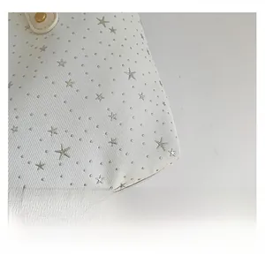 Gros plan sur tissu texturé blanc avec clous métalliques argentés et rivets en étoile