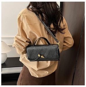 Detailed view of black woven texture leather bag with a gold knot-shaped metal clasp