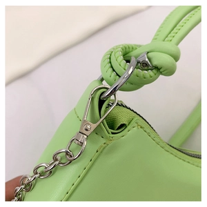 Detail of light green bag with silver chain hook, leather knot handle, and fine stitching