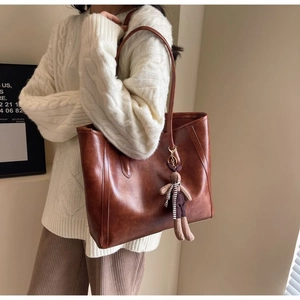 Brown leather tote bag featuring a cute bunny charm during an autumn style photo shoot