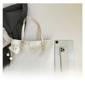 Détail d'un sac cabas en toile blanche à motif d'étoiles avec plaque logo dorée