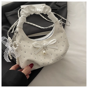 Detail of white jacquard fabric handbag with silver beads, pearl pendant and lace bow
