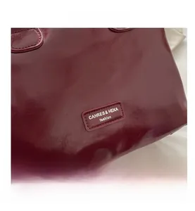 Gros plan sur un sac à main en cuir verni bordeaux avec étiquette de marque cousue