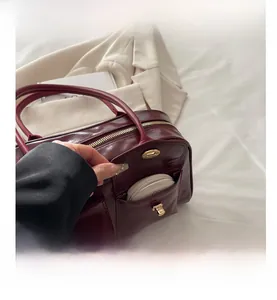 Detail der burgunderroten Handtasche mit Goldschloss und praktischem Fach für Kosmetik