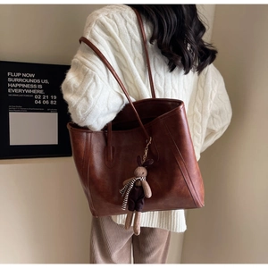 Detail of vintage brown leather tote bag with a cute plush bunny charm on shoulder