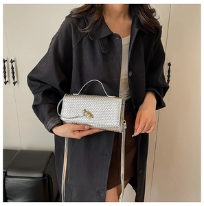 Detailed view of silver woven texture bag with an elegant gold metallic knot clasp buckle