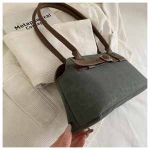 Detail of vintage green suede shoulder bag with brown leather handles and buckle accent