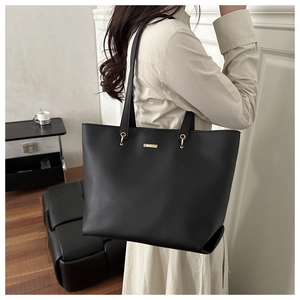 Detailed shot of premium black tote bag showing gold hardware and leather texture