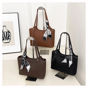 Detailed view of leather tote bags in brown, tan, and black with decorative scarves