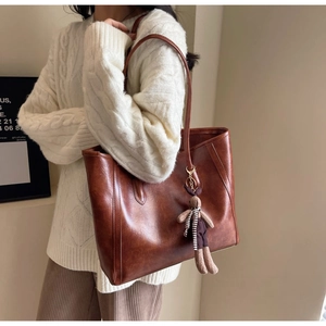 Detail of vintage brown tote bag with premium PU leather texture and plush bunny charm