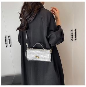 Detailed view of silver woven texture purse with gold knot buckle on black shirt