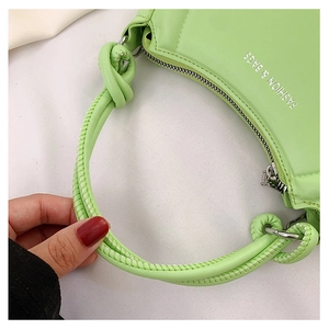Detail of light green fashion bag showing knotted shoulder strap and silver zipper
