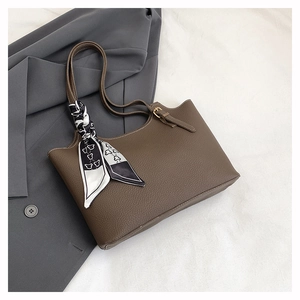 Detail of dark brown pebble leather tote bag with a decorative silk scarf on the handle