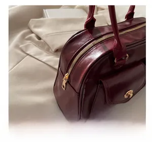 Details des goldenen Reißverschlusses und weinroten Leders der Boston-Handtasche