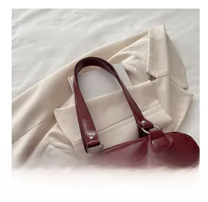 Détail macro de la texture du sac en cuir bordeaux sur blazer beige avec livres