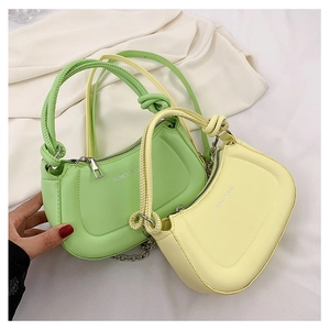 Detail of light green and pale yellow PU leather bags with knot handle and metal chain