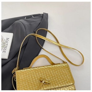 Macro detail of gold woven texture bag with artistic twist clasp on a gray blazer