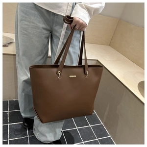 Detail of dark brown PU leather tote bag showing golden ring hardware and slim handle