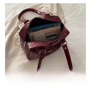 Vue intérieure du grand sac bandoulière rouge foncé avec divers articles et zip argenté