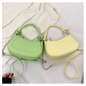 Flat lay of crescent PU leather bags in green and yellow with knot handles and chain
