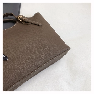 Detail of dark brown lychee leather bag with white contrast stitching and gold buckle