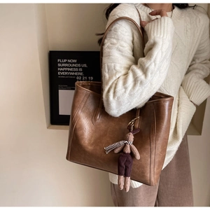 Detail of vintage brown tote bag texture with cute bunny charm on slim shoulder strap