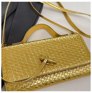 Detailed close-up of golden woven texture on a handbag with a knot-shaped metal clasp
