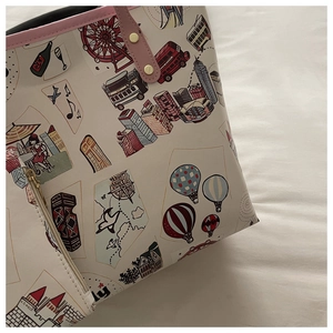 Detail of cartoon travel print tote bag showing pink straps and matching inner pouch