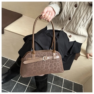 Detail of leopard print suede shoulder bag featuring brown leather strap and metal buckle