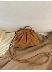 Borsa a nuvola in camoscio marrone su un trench con un libro aperto in stile lifestyle