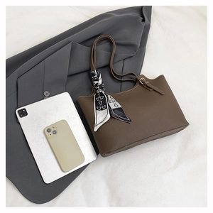 Detail of dark brown leather tote bag featuring a decorative black and white silk scarf
