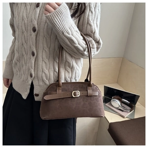Macro shot of the dark brown suede fabric texture and golden metal buckle on the shoulder bag