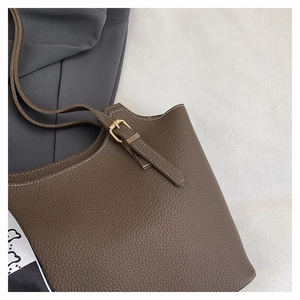 Detail of dark brown lychee texture leather tote bag with white contrast stitching