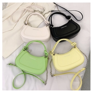 Detail of half-moon leather handbags in green, yellow, white and black with chain straps