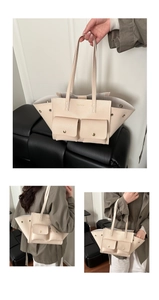 Detail of cream white tote bag with front snap pockets and pebbled leather texture