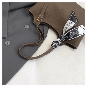 Detail of dark brown pebble leather tote bag with printed silk scarf on the handle