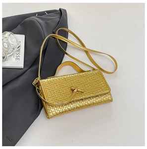 Detailed close-up of golden woven texture and elegant knot buckle on a luxury clutch